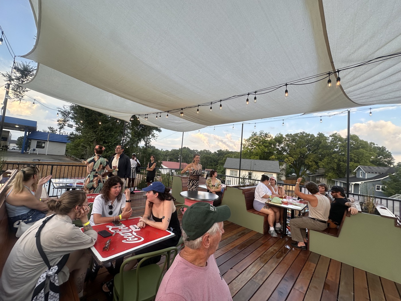 Rooftop deck packed with guests under string lights at sunset