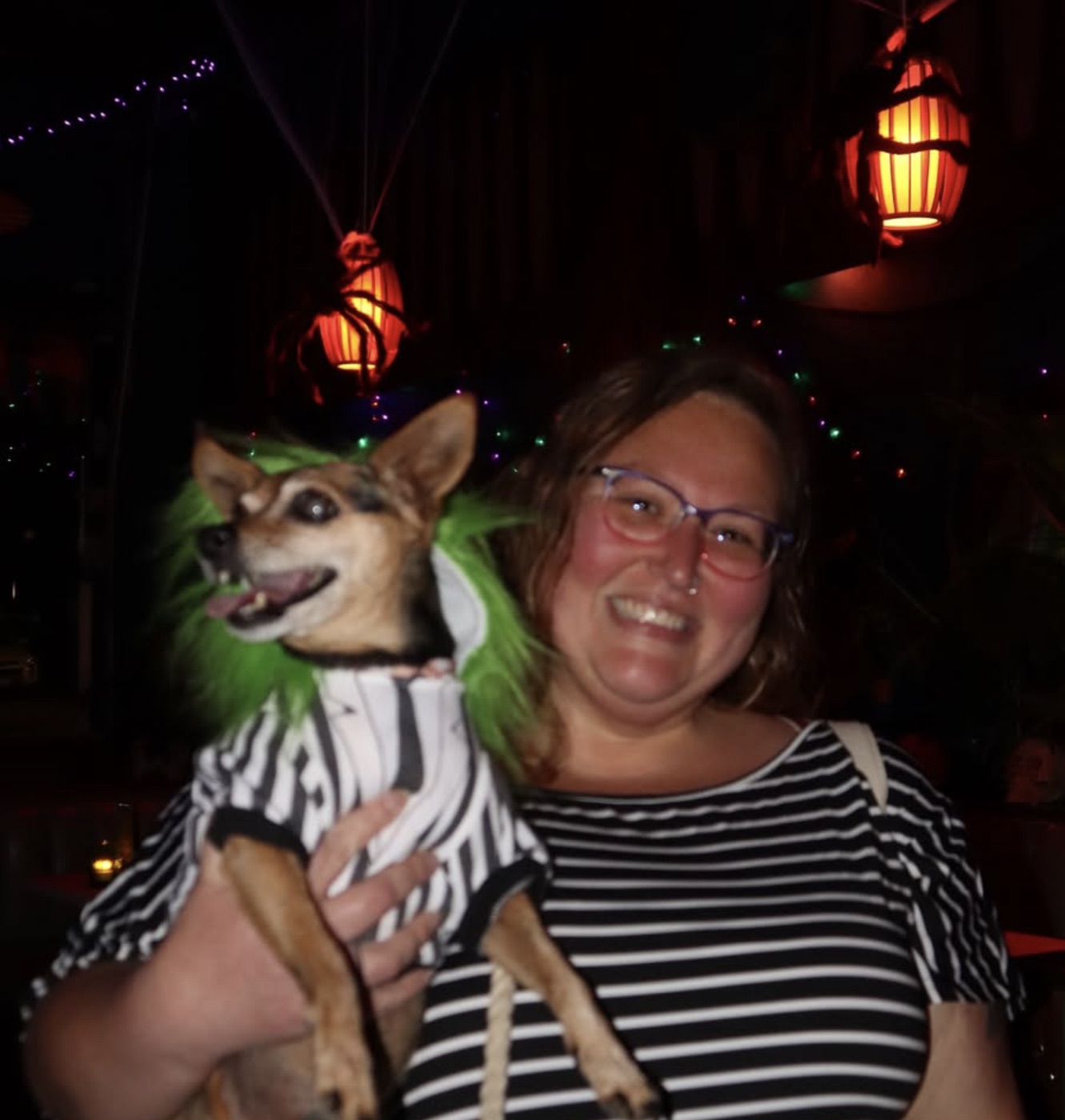 Guest holding her dog in a costume at Potions and Paws